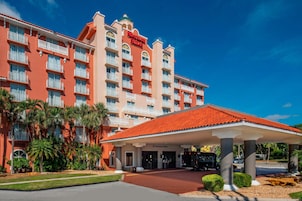 Un hotel con fachada roja, varios balcones y un área de entrada cubierta.