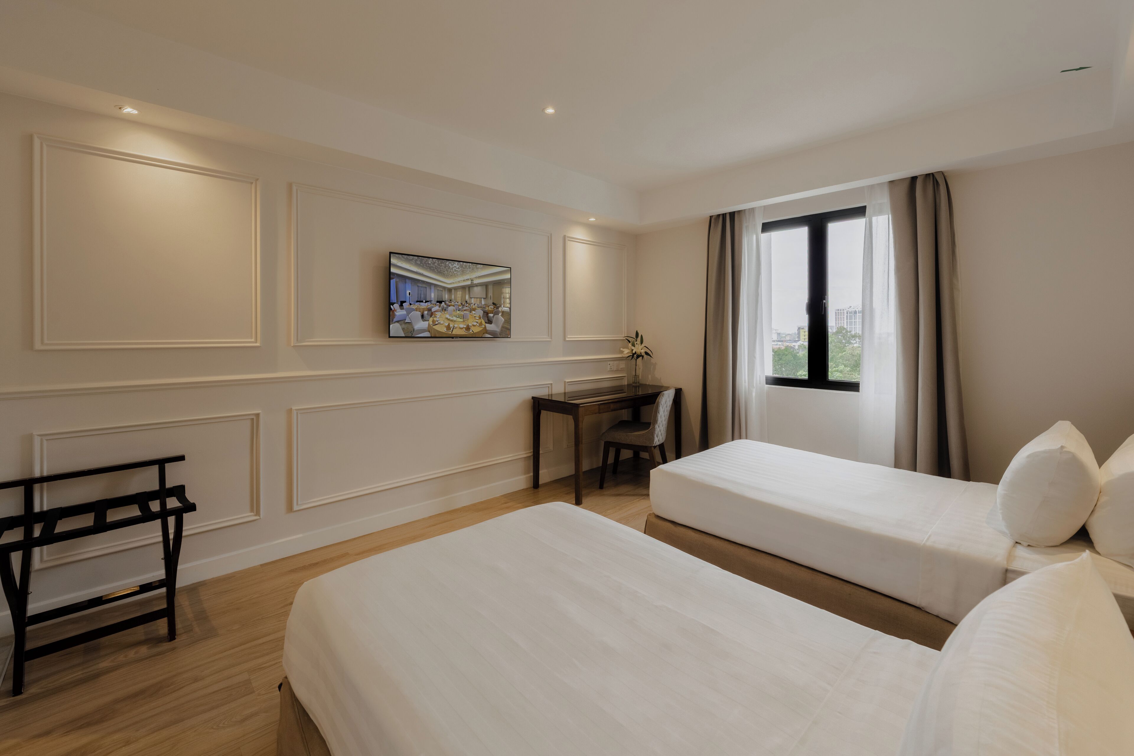 Habitación de hotel con dos camas, un escritorio, una silla y un cuadro en la pared.