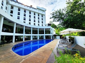 Un hôtel moderne doté d’une grande piscine intérieure, de nombreux balcons et d’espaces extérieurs aménagés pour se détendre.