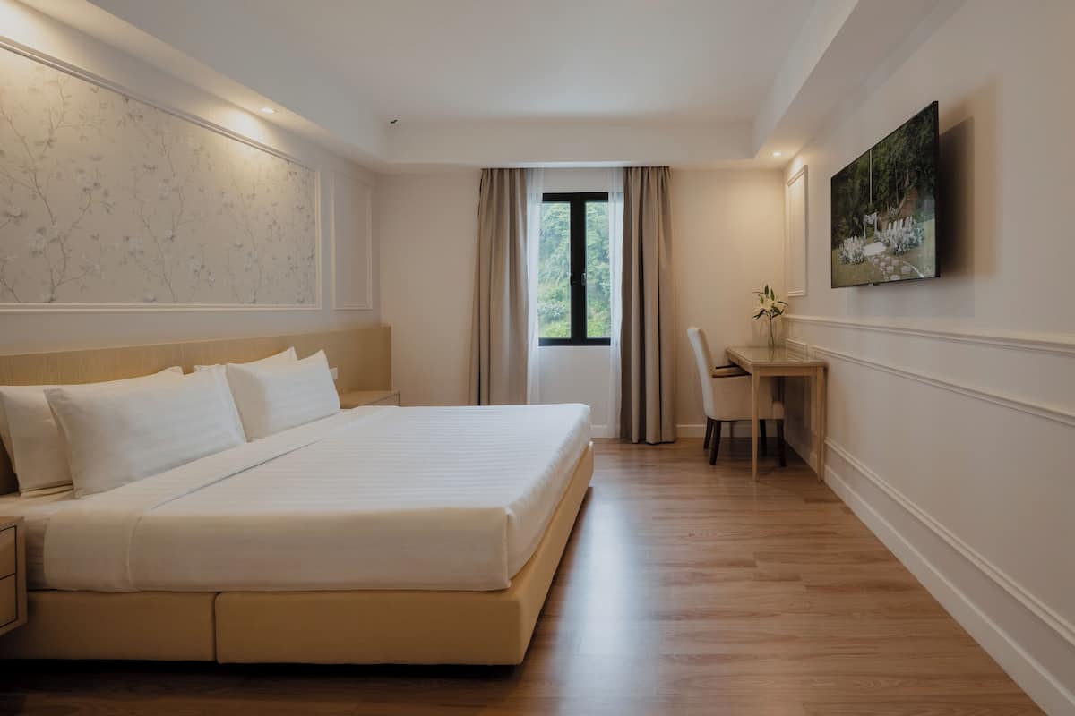 Ein Hotelzimmer mit einem großen Bett, einem Schreibtisch und einem an der Wand montierten Fernseher.