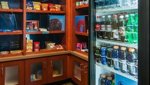 A vending machine stocked with beverages and snacks, surrounded by wooden cabinets with various packaged goods.