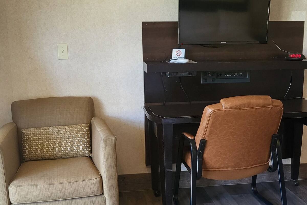 A living room with a sofa, a chair, a TV, and a desk.