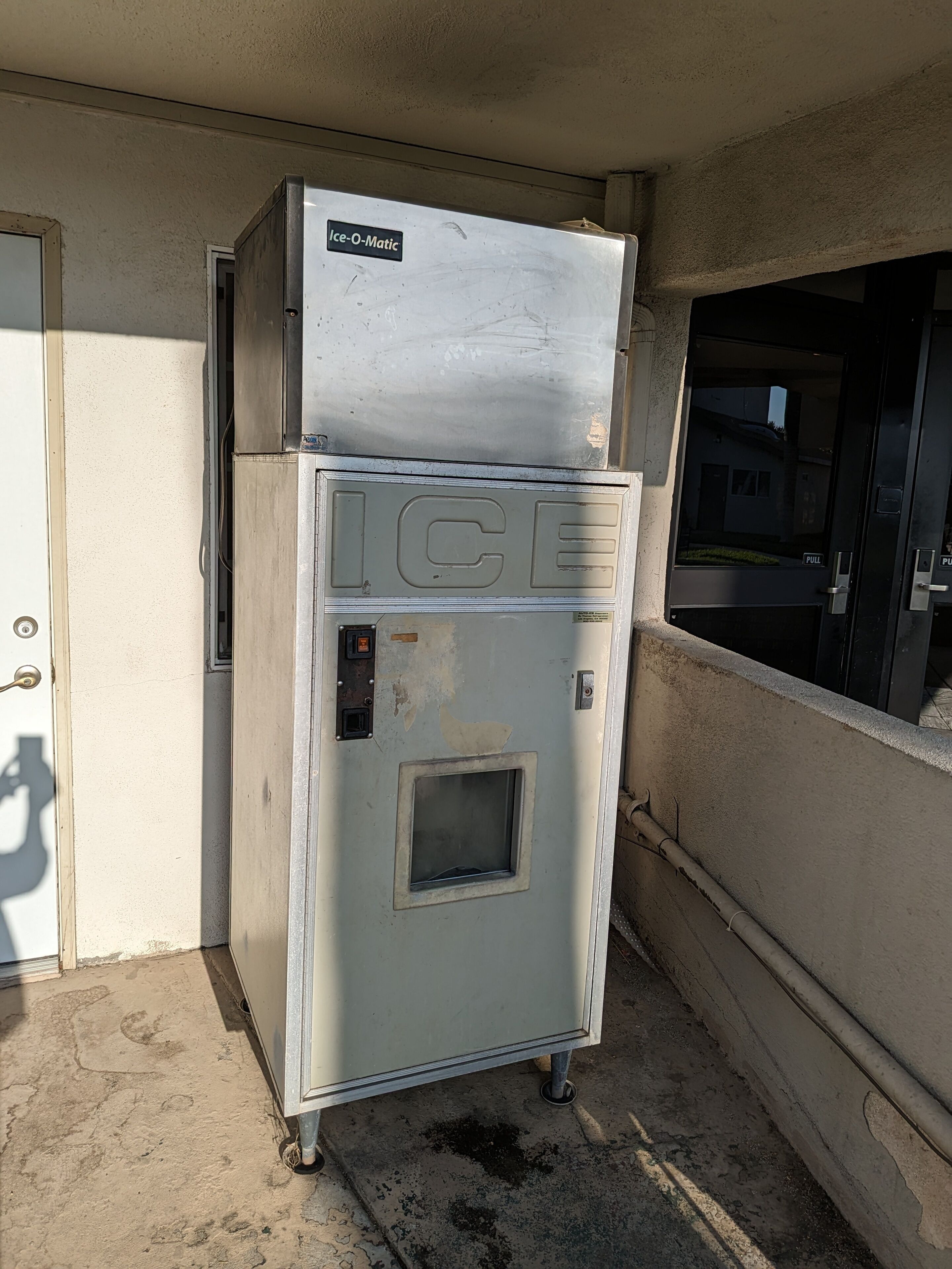 Une machine à glaçons commerciale, avec une enseigne indiquant « Ice-O-Matic » et une grande étiquette « GLACE » sur la façade.