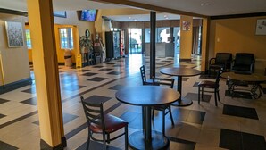 Um lobby amplo com piso xadrez, várias áreas de estar e um caixa eletrônico visível.