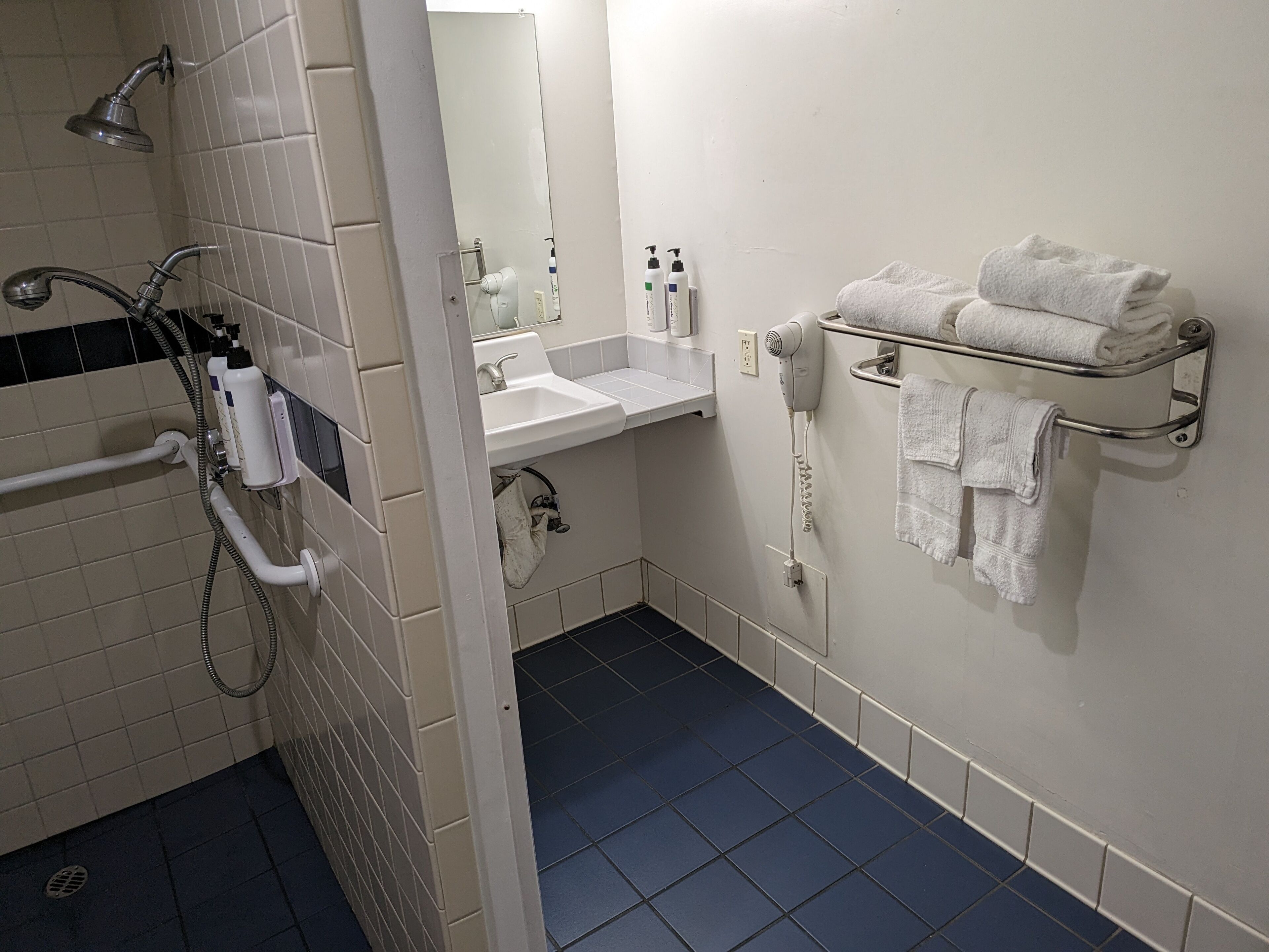 Un baño con ducha, lavamanos y toallero.