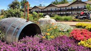 A hotel with multiple balconies, a garden with colorful flowers, and a golf cart in the foreground.