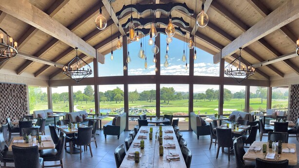 Une salle à manger spacieuse, dotée de hauts plafonds et de grandes fenêtres offrant une vue sur un terrain de golf.