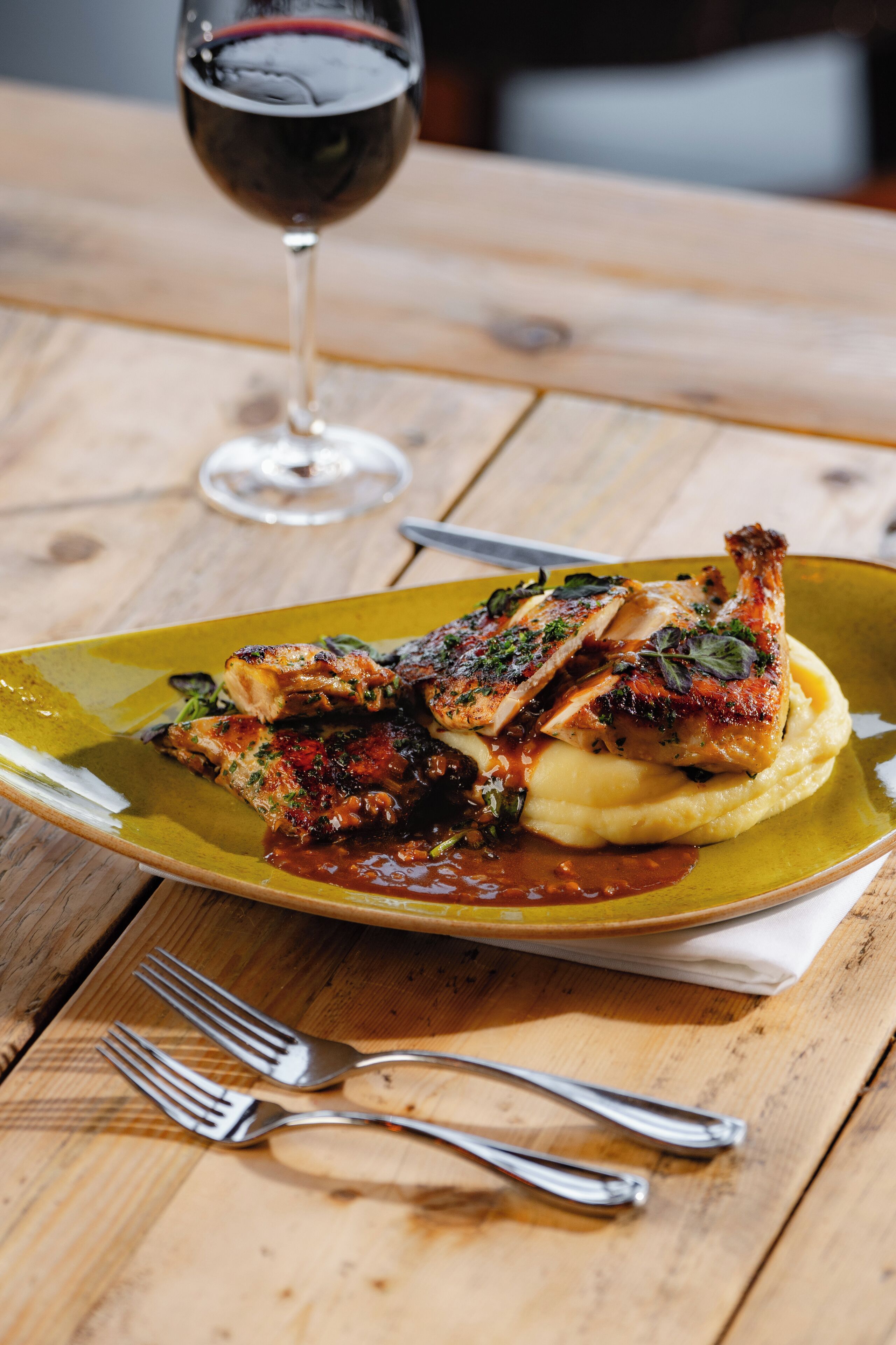 A plate of food with a glass of red wine on a wooden table.