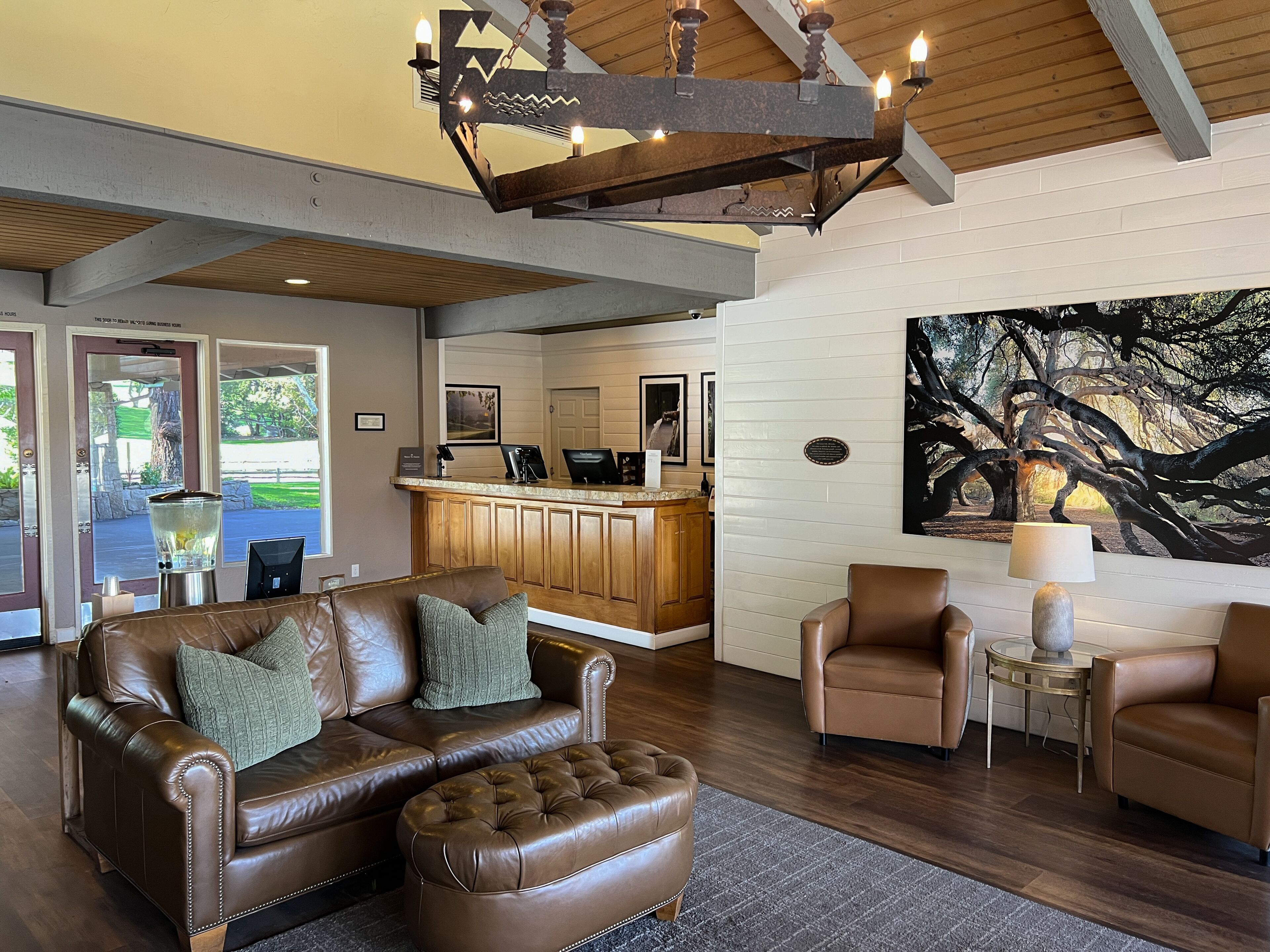A spacious living area with a leather sofa, a coffee table, and a painting of a tree.