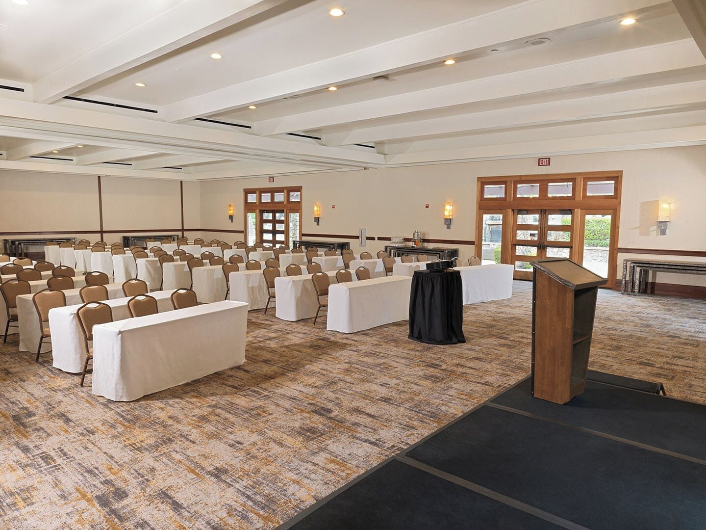 A conference room with rows of tables, chairs, and a podium.