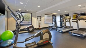 Un gimnasio con cintas de correr, elípticas y pelotas de ejercicios.