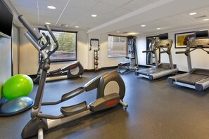 Una palestra con tapis roulant, macchinari ellittici e palle da ginnastica.