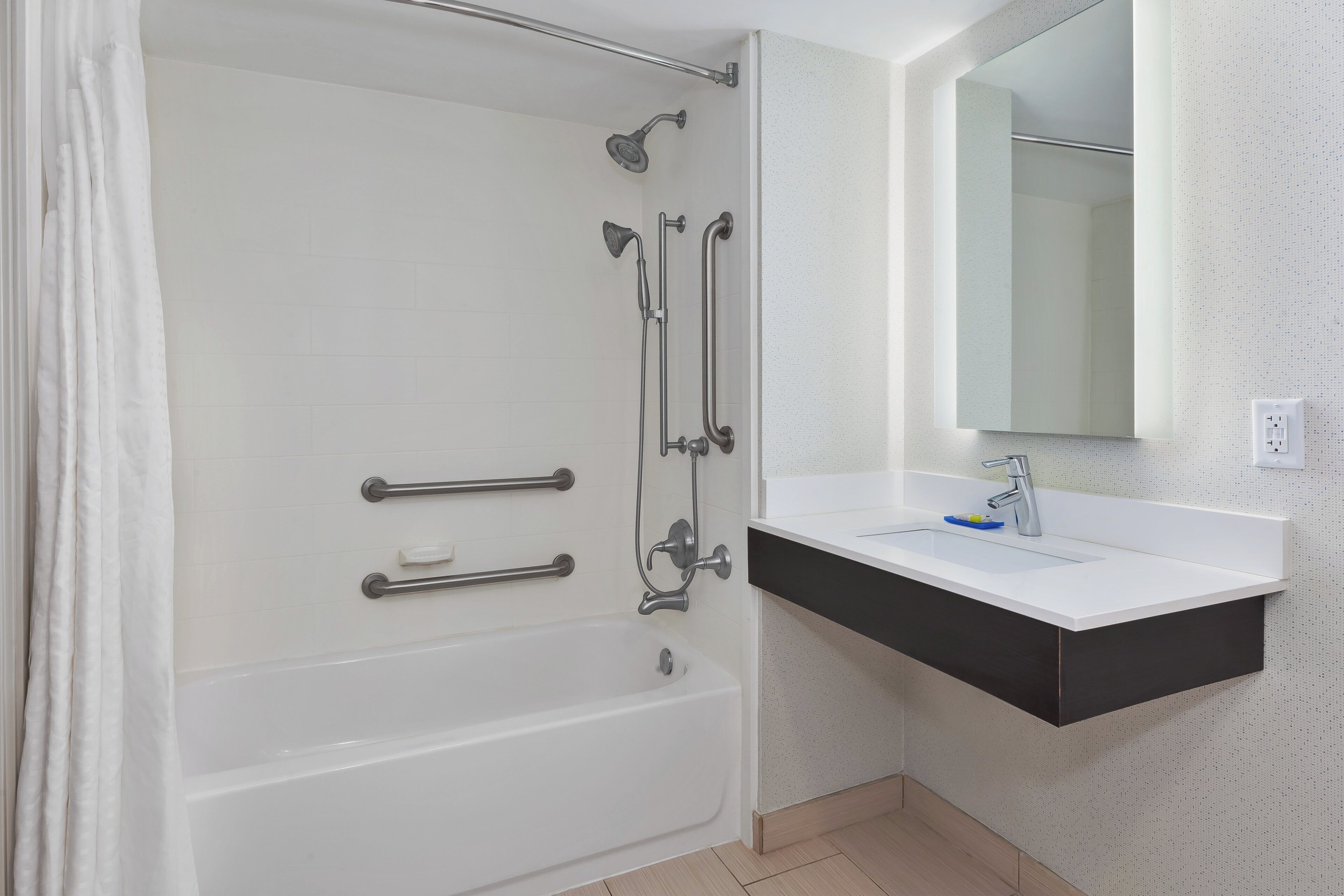 A modern bathroom with a bathtub, a shower, and a sink with a mirror above it.