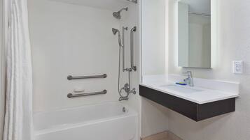 A modern bathroom with a bathtub, a shower, and a sink with a mirror above it.