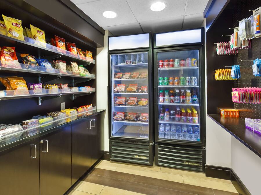 A snack and beverage section with shelves of chips, a refrigerated display with drinks, and a wall with hanging items.
