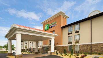A Holiday Inn Express hotel with a covered entrance, a stone facade, and a parking lot.