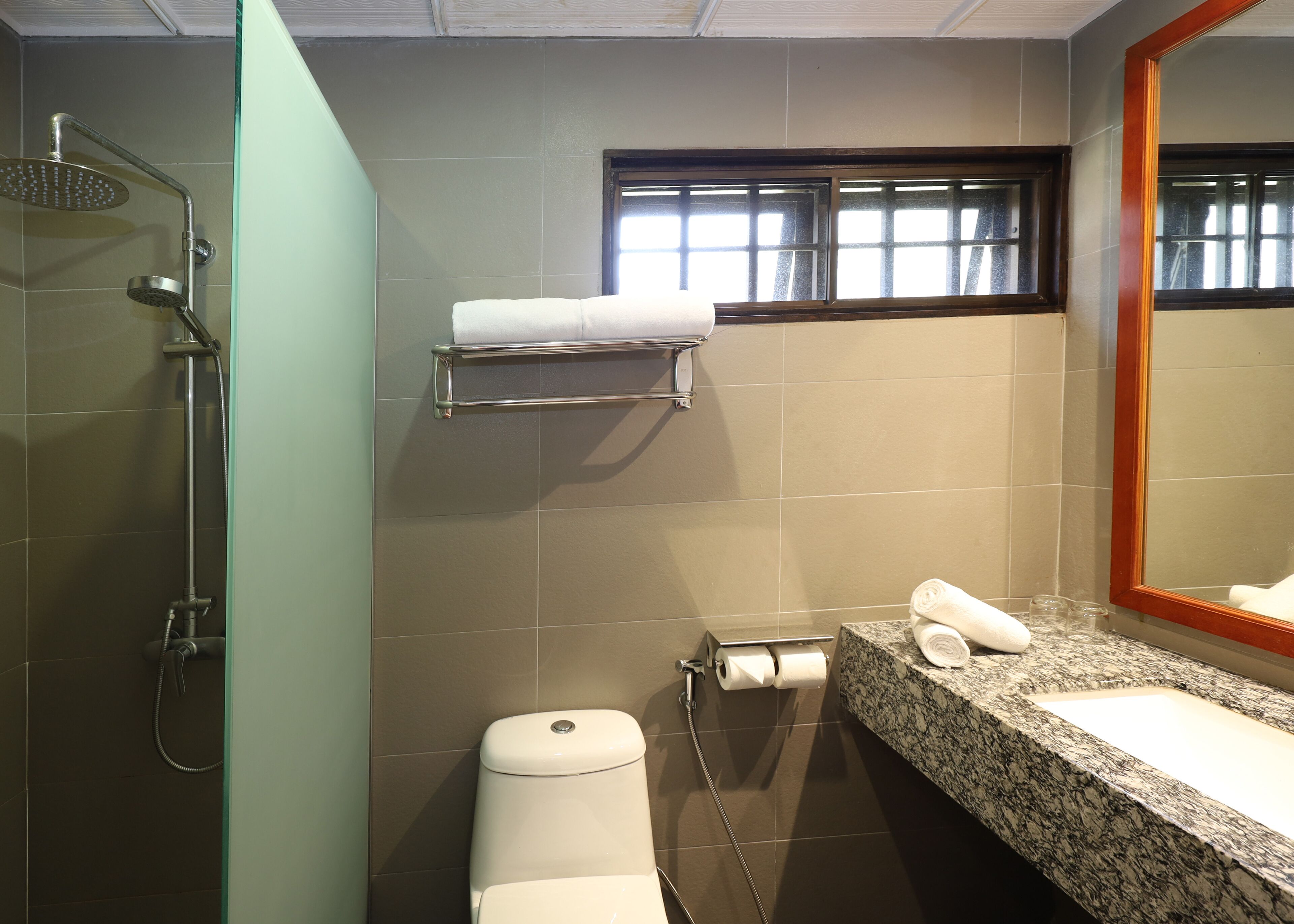 A bathroom with a shower, toilet, sink, and a towel rack.