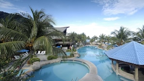 A resort with a large pool, palm trees, and a beach view.