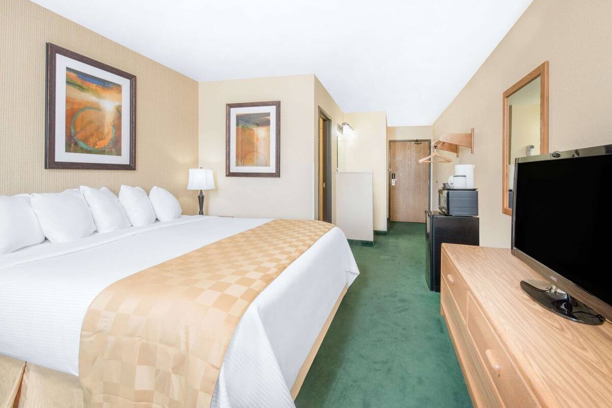 Een hotelkamer met een groot bed, een televisie, een bureau en kunst aan de wanden.