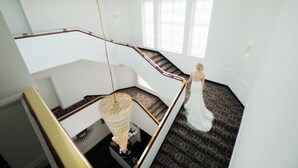 Una escalera con alfombra estampada, un candelabro y una pared blanca.