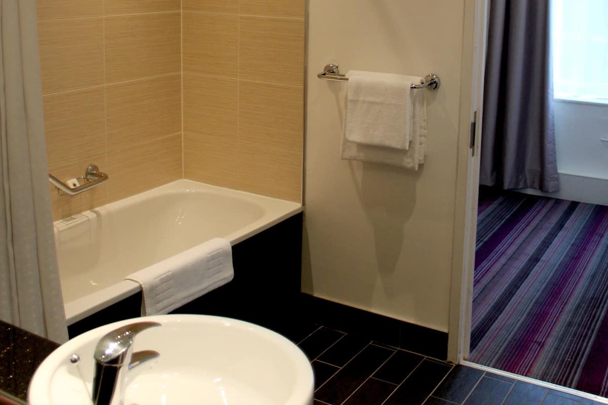 A bathroom with a bathtub, a sink, and a shower area.