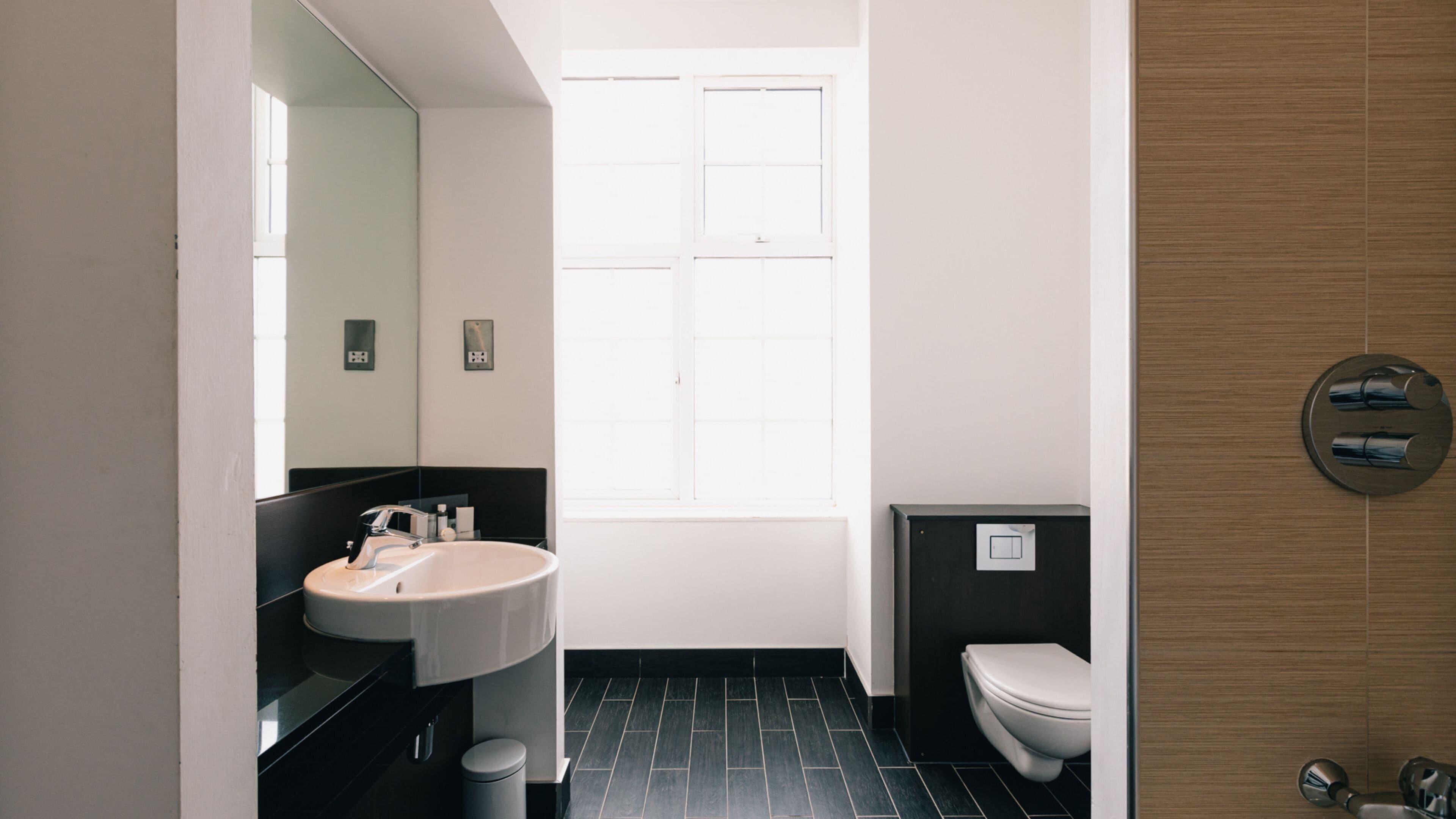 Une salle de bain moderne avec un lavabo, un miroir et des toilettes.