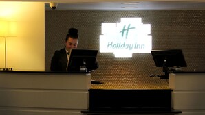 Mostrador de recepción de Holiday Inn, con una pared texturizada y un letrero grande iluminado.