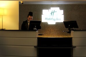 Mostrador de recepción de Holiday Inn, con una pared texturizada y un letrero grande iluminado.