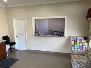 A room with a door, a desk with a computer, a chair, a small window, and a wall with a bulletin board. - Paso Robles Travelodge (Paso Robles)