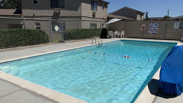 A swimming pool with clear water, a diving board, and a covered seating area. - Paso Robles Travelodge (Paso Robles)