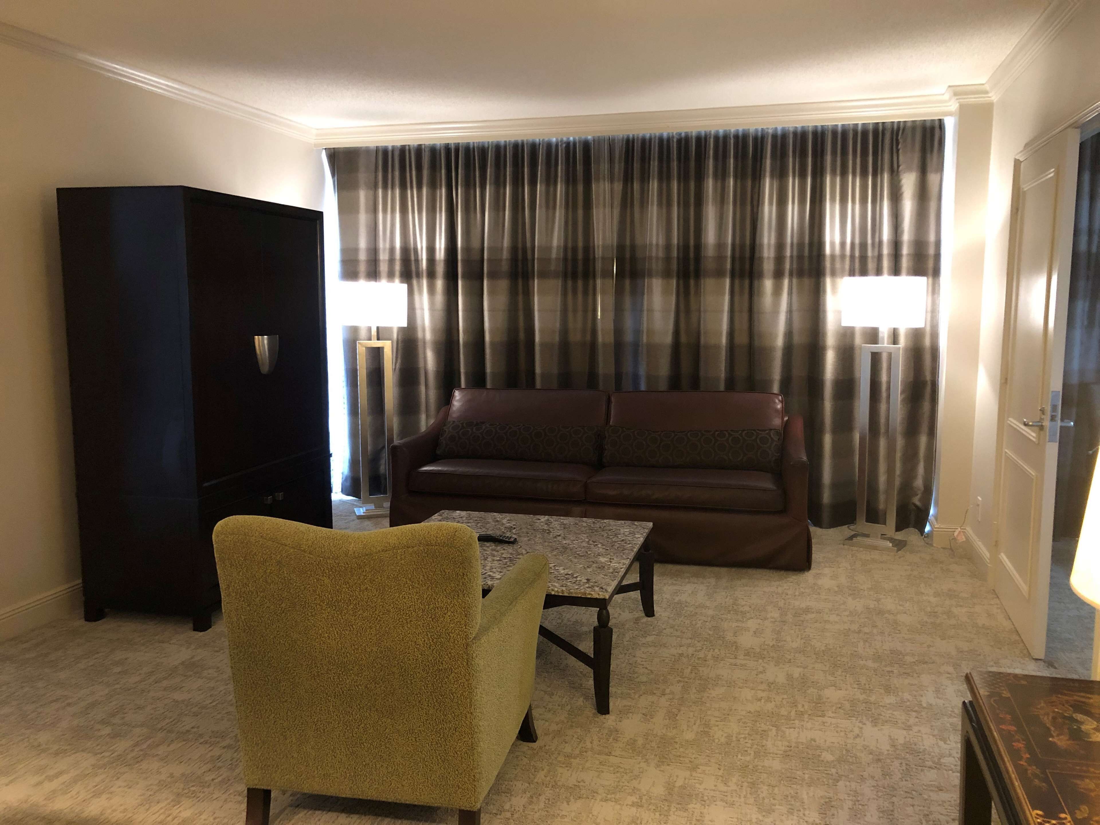 A living room with a sofa, armchair, coffee table, and a television.