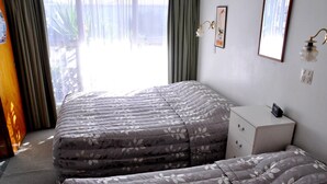 Habitación de hotel con una cama grande, una mesita de noche y vistas al exterior.