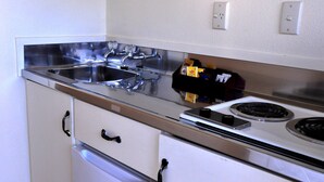 Una cocina con un lavaplatos de acero inoxidable, estufa y refrigerador.