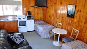 Una habitación compacta con kitchenette, una cama, un sofá y una pequeña mesa.