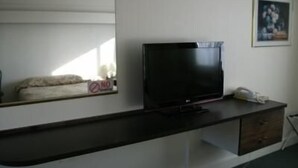 Una habitación con una televisión de pantalla plana sobre un mueble de madera oscura, un cuadro en la pared y un cartel de 'No Smoking'.