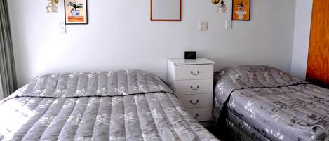 Un dormitorio con dos camas, un aparador y obras de arte colgadas en la pared.