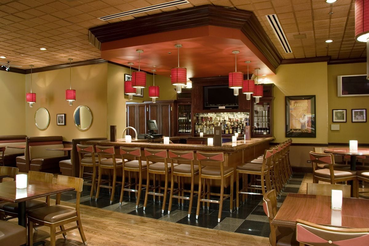 A restaurant with booths and tables, a bar area, and a television screen.