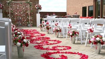 Ein schöner Brautgang im Freien mit weißen Stühlen und Blumenschmuck.
