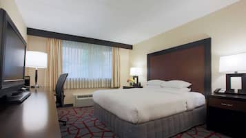 Une chambre d’hôtel avec un grand lit, un bureau avec un ordinateur, une télévision et un téléphone.