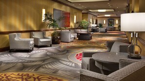 Eine Hotelhalle mit Sitzbereichen, einem gemusterten Teppich und einem großen Spiegel.