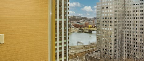 A high-rise building with a view of a river and a bridge in the background.