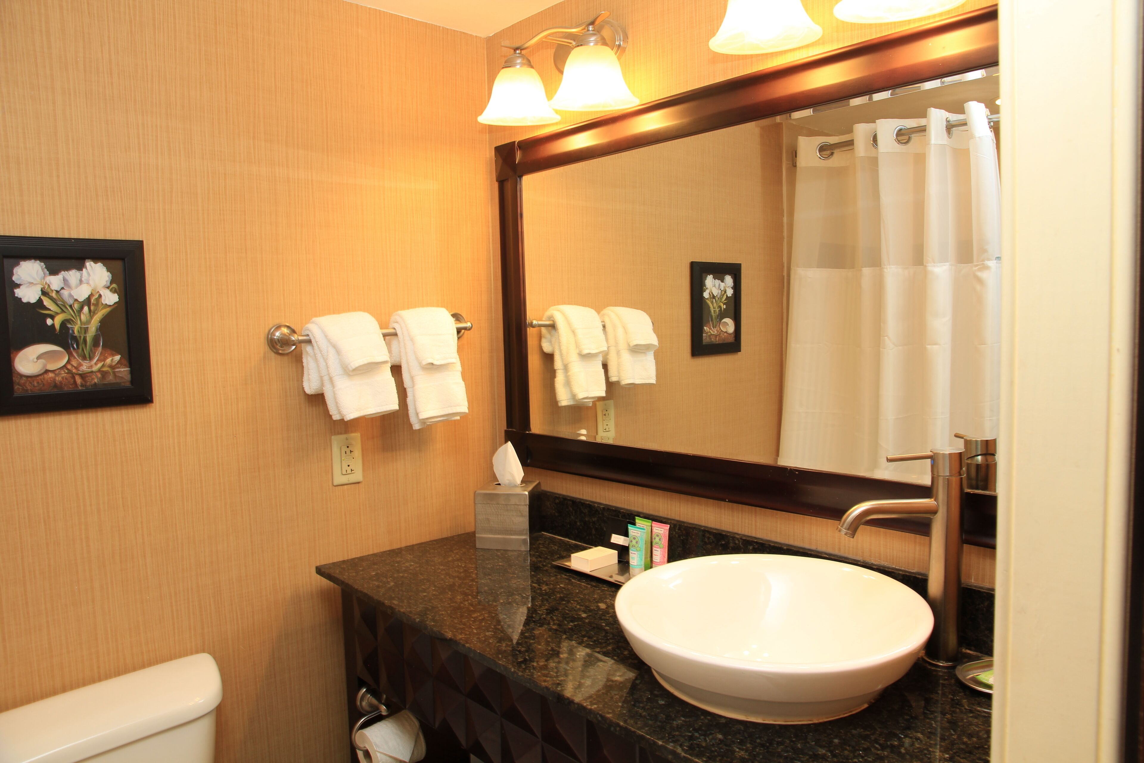 A bathroom with a large mirror, a sink, and two towels hanging on the wall.