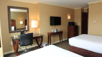 Une chambre d’hôtel équipée d’un bureau, d’une chaise, de deux lits, d’une télévision et d’un miroir.