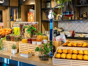 A buffet with various food items and beverages, including fruits, pastries, and condiments.
