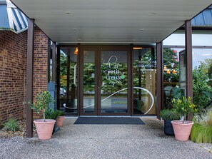 A hotel entrance with a glass door, a reception desk, and potted plants. - Ibis Amboise (Amboise)