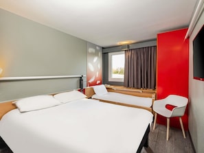 Habitación de hotel con una cama grande, un escritorio, una silla y una ventana con cortinas.