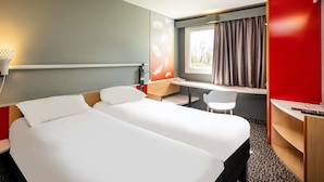 A hotel room with a bed, desk, chair, and a window with curtains. - Ibis Amboise (Amboise)