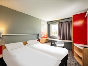 A hotel room with a bed, desk, chair, and a window with curtains. - Ibis Amboise (Amboise)
