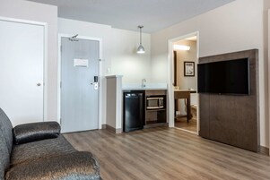 A compact living space with a kitchenette, a flat-screen TV, and a seating area.