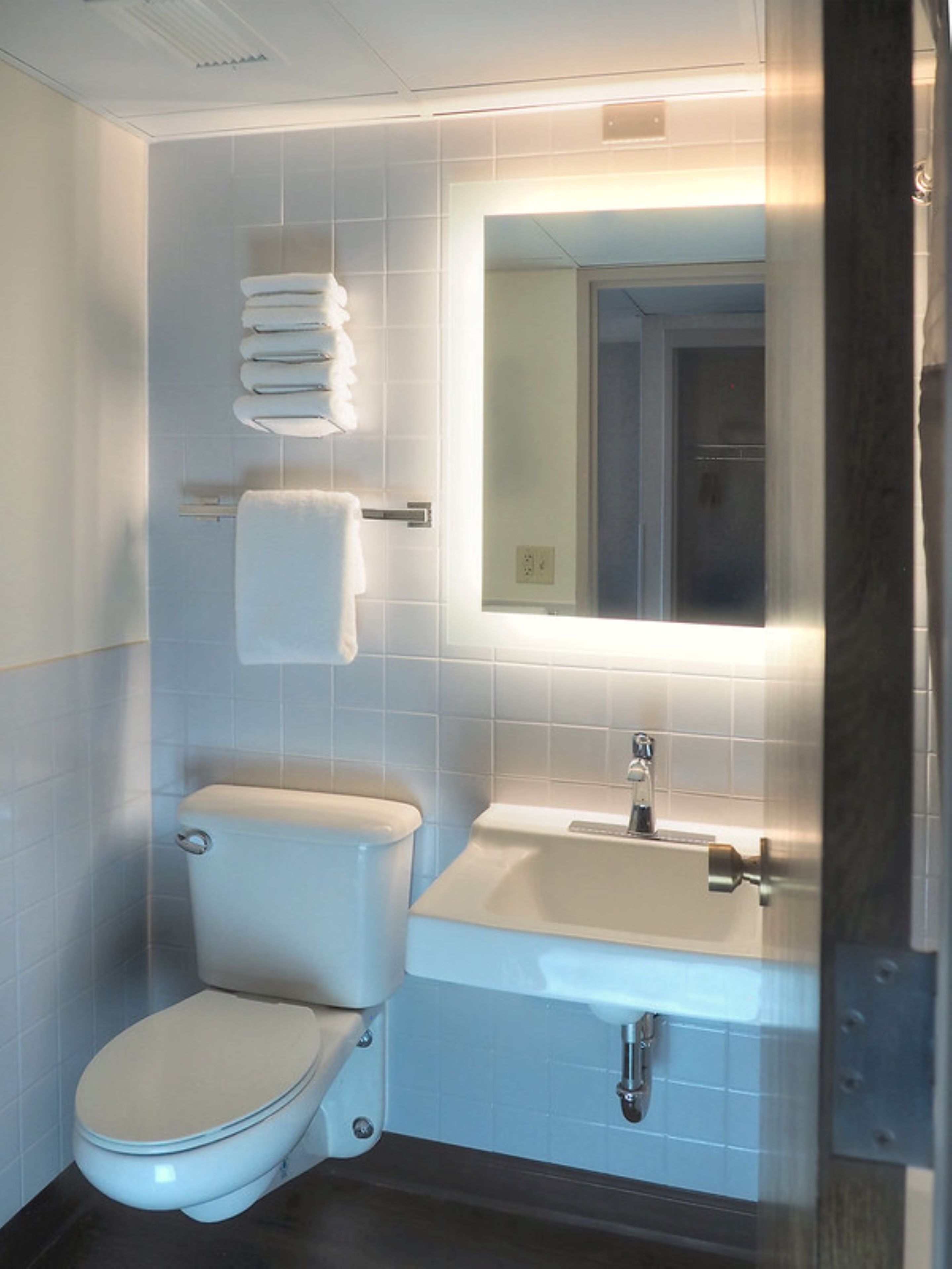 Un baño moderno con inodoro, lavabo y espejo.